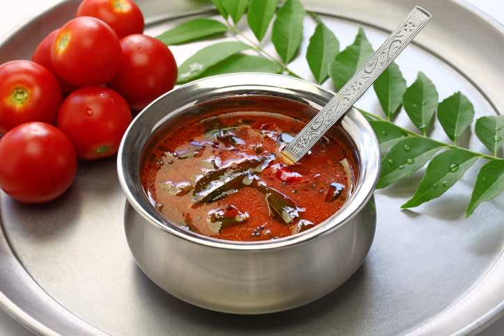 small bowl of red soup with tomatoes on the side