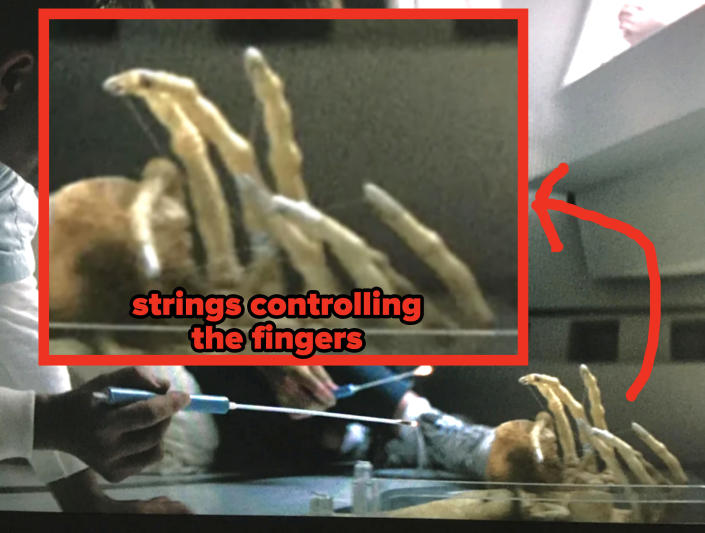 You can faintly see the strings being used to control the alien's fingers like a marionette