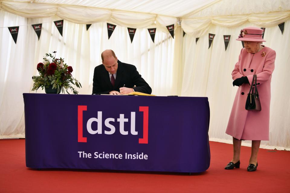 Britain's Queen Elizabeth II (R) stands by as Britain's Prince William, Duke of Cambridge (L) signs a visitor's book during their visit to the Defence Science and Technology Laboratory (Dstl) at Porton Down science park near Salisbury, southern England, on October 15, 2020. - The Queen and the Duke of Cambridge visited the Defence Science and Technology Laboratory (Dstl) where they were to view displays of weaponry and tactics used in counter intelligence, a demonstration of a Forensic Explosives Investigation and meet staff who were involved in the Salisbury Novichok incident. Her Majesty and His Royal Highness also formally opened the new Energetics Analysis Centre. (Photo by Ben STANSALL / POOL / AFP) (Photo by BEN STANSALL/POOL/AFP via Getty Images)