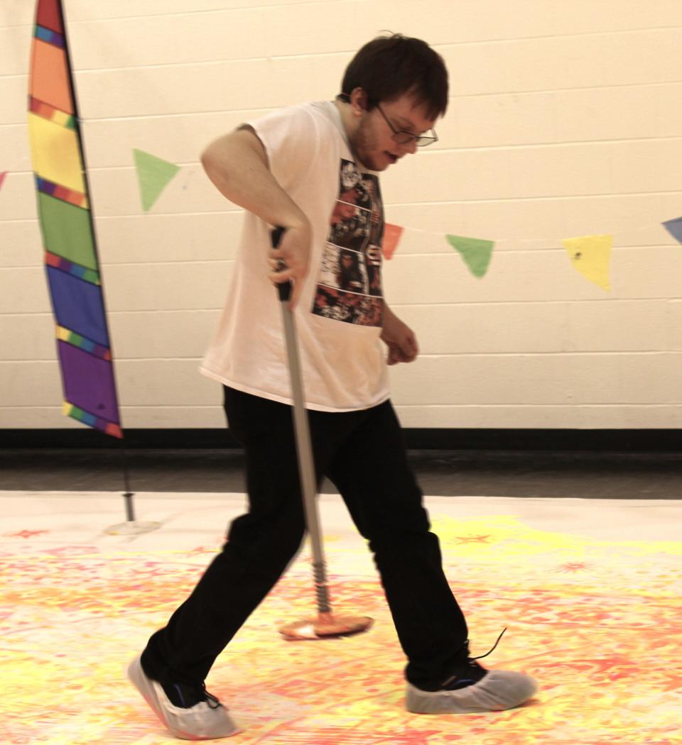 Evan, a Monroe County Intermediate School District student, uses a Pogo Paint Pole to stamp images on a giant canvas.