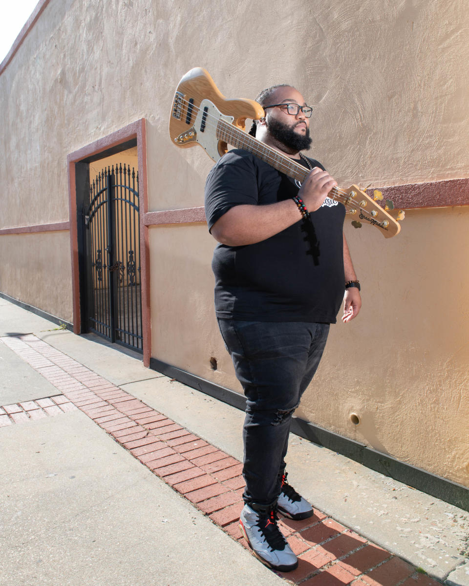 Musician Chris Snowden poses with his bass guitar in front of historic Belmont-DeVilliers music clubs in Pensacola on Wednesday, Sept. 6, 2023.
