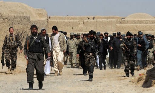 An Afghan delegation walks with locals after a gathering for a memorial ceremony at a mosque in Alokozai village in Panjwayi district, Kandahar province, on March 13, 2012. Gunmen on Tuesday attacked the memorial service for 16 villagers killed by a US soldier, shooting dead a member of the Afghan military and wounding a policeman in a hail of gunfire