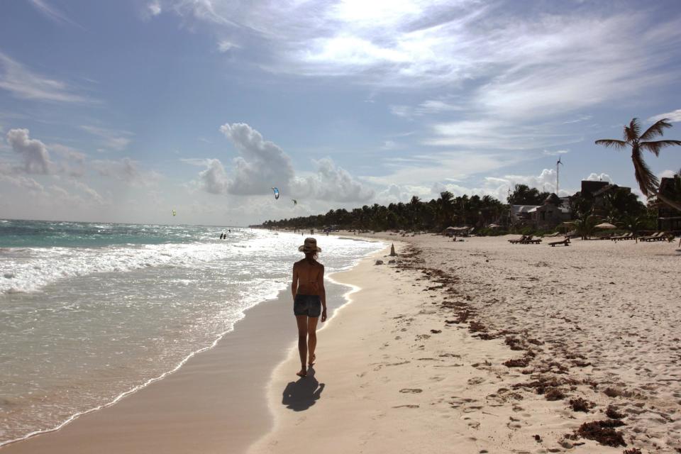 In this Jan. 4, 2013, photograph, a woman walks along the beach in Tulum, Mexico. Despite its proximity to Cancun and its fellow party neighbor Playa del Carmen, Tulum attracts a different spring break crowd to its turquoise waters and white sandy beaches, with a mix of bohemians, well-pocketed New Age types and sun-seekers. (AP Photo/Manuel Valdes)