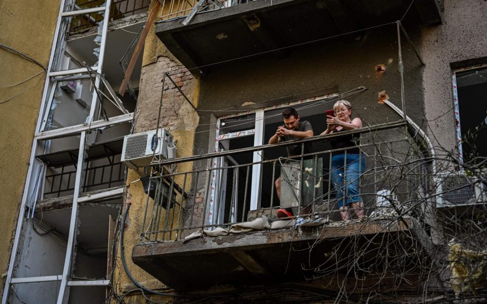 Residents stand on the balcony of their destroyed home following a shelling in Kharkiv -  SERGEY BOBOK/ AFP