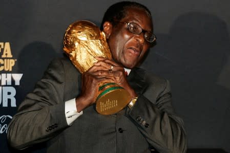 FILE PHOTO: Zimbabwe's President Robert Mugabe clasps the FIFA soccer World Cup trophy in Harare