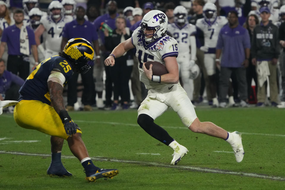 TCU quarterback Max Duggan (15) runs as Michigan linebacker Junior Colson (25) defends during the second half of the Fiesta Bowl NCAA college football semifinal playoff game, Saturday, Dec. 31, 2022, in Glendale, Ariz. (AP Photo/Rick Scuteri)