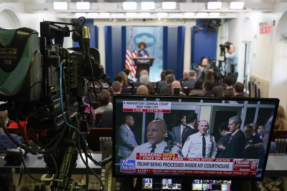 A television broadcasting news of former President Donald Trump’s Manhattan courthouse appearance is seen on a video monitor as White House press secretary Karine Jean-Pierre speaks during a press briefing at the White House, Tuesday, April 4, 2023, in Washington.