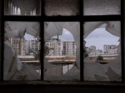 Kufr Aqab, a Palestinian neighborhood of Jerusalem located on the West Bank side of Israel's separation barrier, is seen through a broken window of the city's shuttered Atarot airport, Monday, Jan. 31, 2022. Twenty years after Israel decided to built its controversial separation barrier amid a wave of Palestinian attacks, it remains in place, even as Israel encourages its own citizens to settle on both sides and admits tens of thousands of Palestinian laborers. (AP Photo/Oded Balilty)