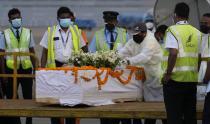 Sri Lankan air port workers stand next to the casket carrying remains of Priyantha Kumara, a Sri Lankan employee who was lynched by a Muslim mob in Sialkot last week after unloading it from an air craft at an air port in Colombo, Sri Lanka, Monday, Dec. 6, 2021. (AP Photo/Eranga Jayawardena)