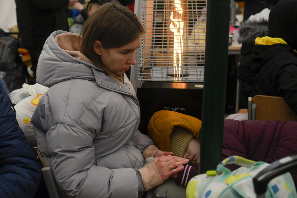 A refugee fleeing the conflict from neighbouring Ukraine holds her child's hand inside a tent at the Romanian-Ukrainian border, in Siret, Romania, Saturday, March 5, 2022. (AP Photo/Andreea Alexandru)