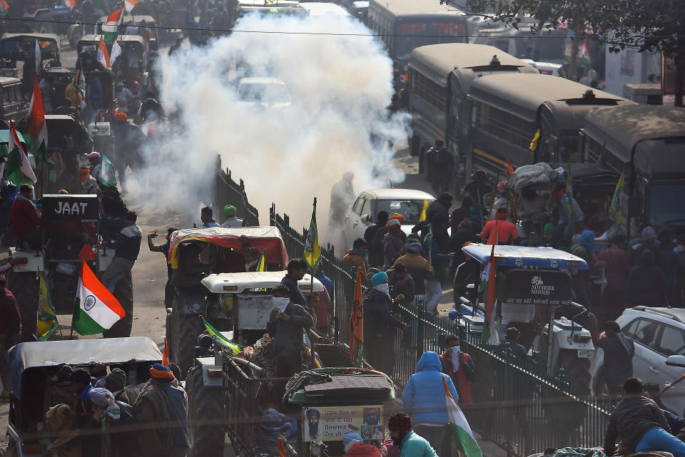 NEW DELHI, INDIA - JANUARY 26: Farmers brave tear gas shells fired by Delhi Police during the tractor march from Tikri border, at Nagloi Crossing, on January 26, 2021 in New Delhi, India. Major scenes of chaos and mayhem at Delhi borders as groups of farmers allegedly broke barricades and police check posts and entered the national capital before permitted timings. Police used tear gas at Delhi's Mukarba Chowk to bring the groups under control. Clashes were also reported at ITO, Akshardham. Several rounds of talks between the government and protesting farmers have failed to resolve the impasse over the three farm laws. The kisan bodies, which have been protesting in the national capital for almost two months, demanding the repeal of three contentious farm laws have remained firm on their decision to hold a tractor rally on the occasion of Republic Day.(Photo by Raj K Raj/Hindustan Times via Getty Images)