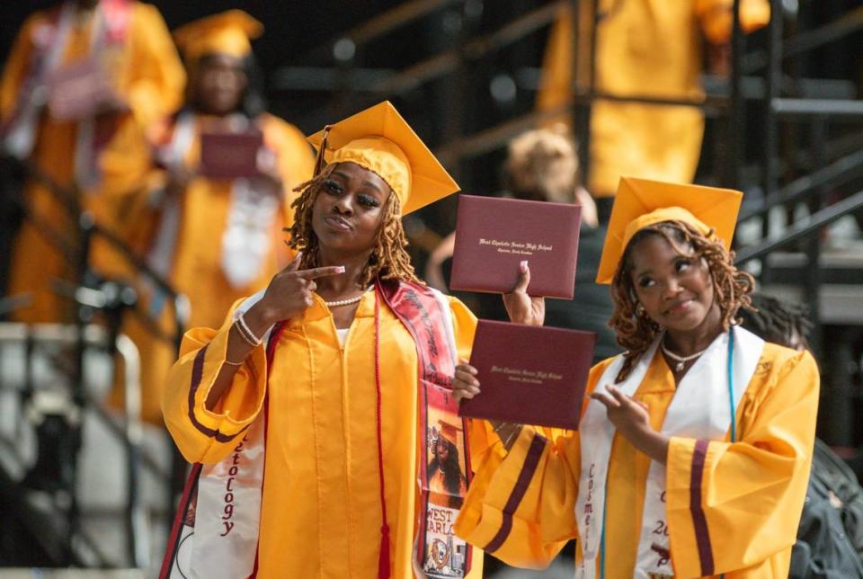 Two West Charlotte High School graduates hold up their diplomas after walking off of the stage on Monday June, 10 in the Bojangles Coliseum.