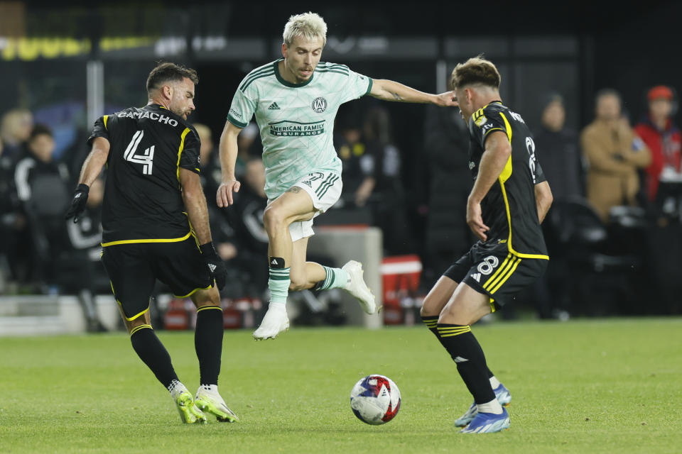 Atlanta United's Saba Lobzhanidze, center, kicks the ball between Columbus Crew's Rudy Camacho, left, and Aidan Morris during the first half of an MLS playoff soccer match, Sunday, Nov. 12, 2023, in Columbus, Ohio. (AP Photo/Jay LaPrete)