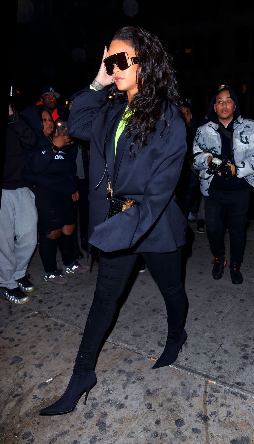 <p>In a neon green top under a baggy navy coat, black skinny pants, high heel boots, an on-trend waist bag, and oversized frames while out in NYC. </p>