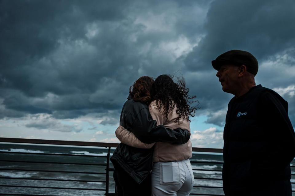 Two teenage girls hugging under a cloudy sky