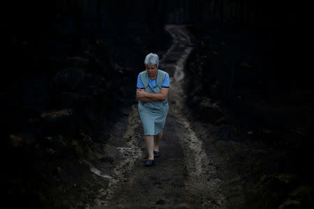 A woman walks through the burnt forest in Vila Nova, near Vouzela, Portugal October 17, 2017. REUTERS/Pedro Nunes