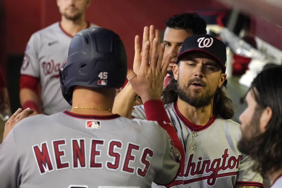 Washington Nationals' Joey Meneses, left, gets a high-five from his pitcher Trevor Williams after scoring their first run against the Arizona Diamondbacks in the second inning during a baseball game, Sunday, May 7, 2023, in Phoenix. (AP Photo/Darryl Webb)