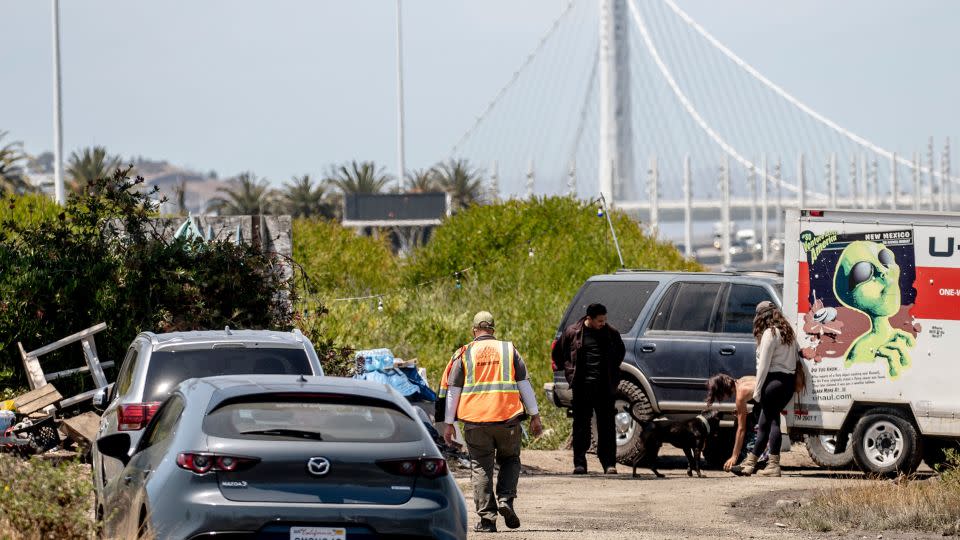 A city worker walks towards a homeless encampment near the San Francisco-Oakland Bay Bridge toll plaza ahead of a scheduled sweep on July 23. - Stephen Lam/San Francisco Chronicle/Getty Images