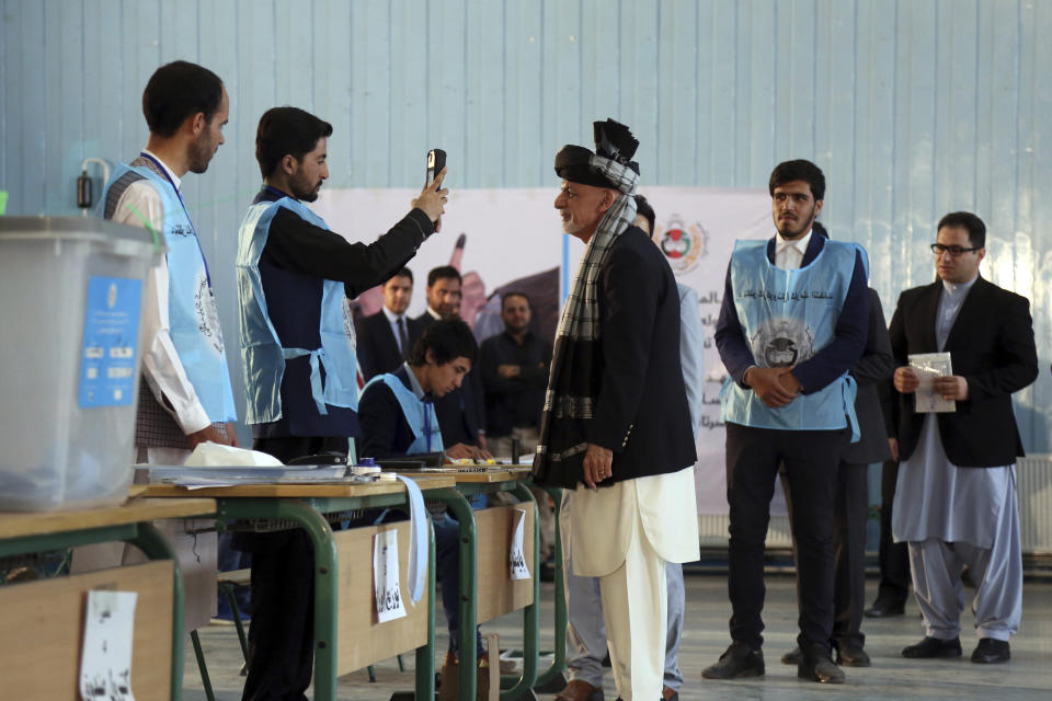 Afghan President Ashraf Ghani, center, poses for a picture, taken by an election official, before casting his vote during the presidential elections in Kabul, Afghanistan, Saturday, Sept. 28, 2019. Afghans headed to the polls on Saturday to elect a new president amid high security and Taliban threats to disrupt the elections, with the rebels warning citizens to stay home or risk being hurt. (AP Photo/Rahmat Gul)