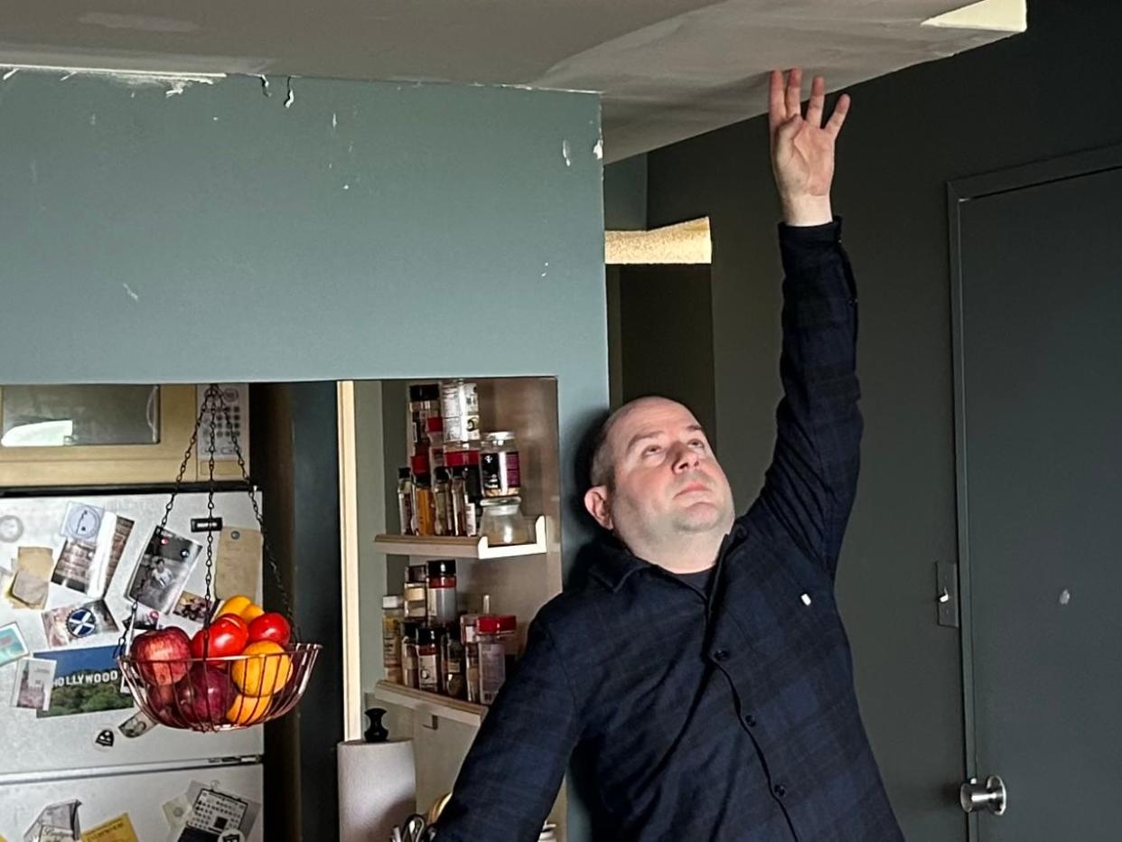 Robbie James at the entrance to his living room. His landlord, TCHC, won permission to lower his ceiling to less than 7 ft. in order to expand the ductwork necessary for his new heat pump - an addition that he says was unnecessary.  (Mike Smee/CBC - image credit)