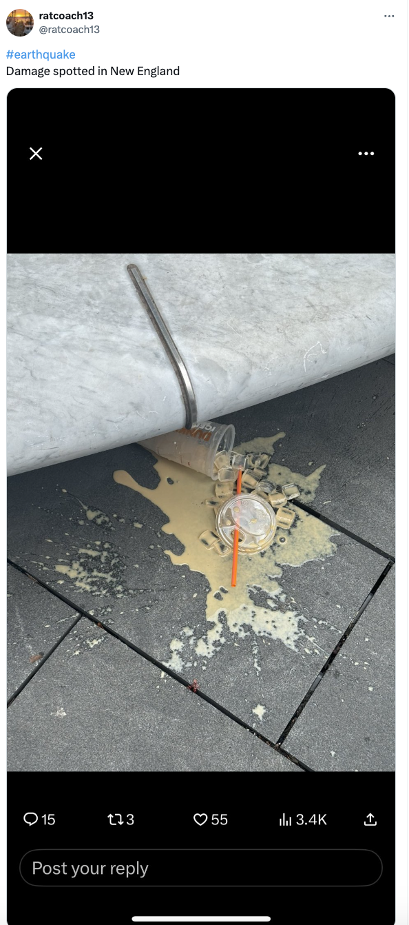 Spilled beverage with straw on the pavement next to a car's tire