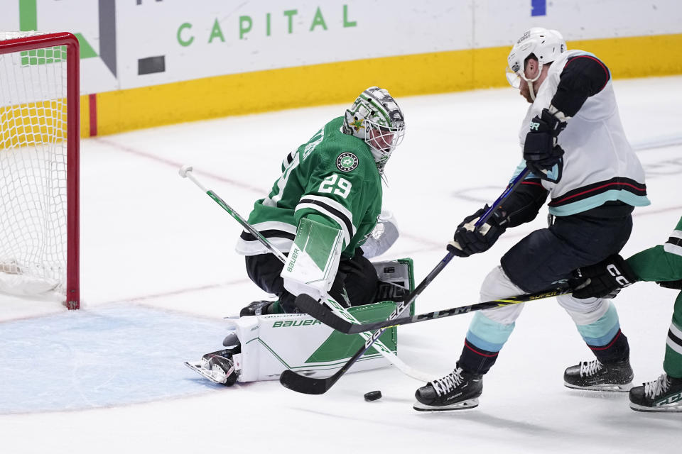 Dallas Stars goaltender Jake Oettinger (29) defends against an attack and a shot by Seattle Kraken defenseman Adam Larsson, right, in overtime of an NHL hockey game, Tuesday, March 21, 2023, in Dallas. Larsson scored on the play in the 5-4 Kraken win. (AP Photo/Tony Gutierrez)