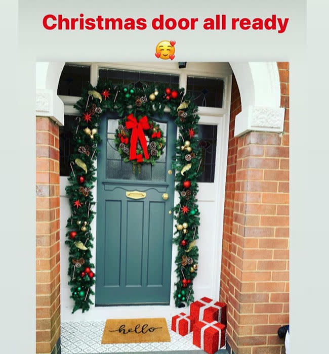 teal door with garland and hello doormat