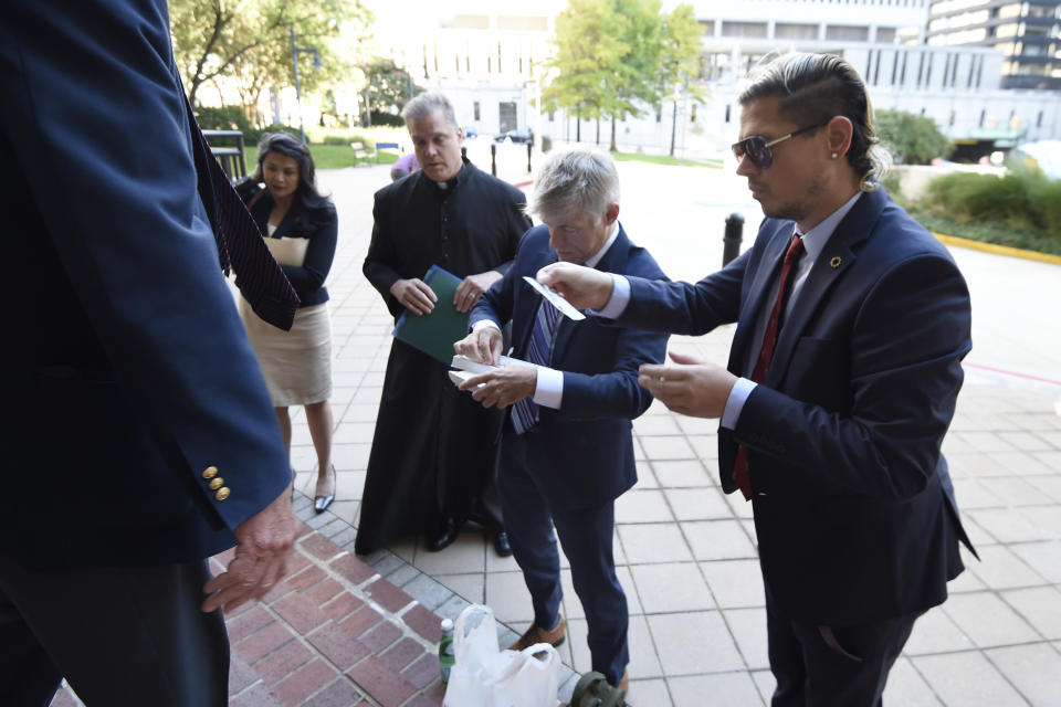 Fr. Paul Kalchik, left,St. Michael's founder and CEO Michael Voris, center, and Milo Yiannopoulos talk with a court officer before entering the federal courthouse, Thursday, Sept. 30, 2021, in Baltimore. U.S. District Judge Ellen Hollander scheduled a hearing Thursday for the lawsuit that rally planners St. Michael’s Media filed against the city. St. Michael's claims city officials cancelled the Nov. 16 rally because they disapprove of the group's religious message. (AP Photo/Gail Burton)