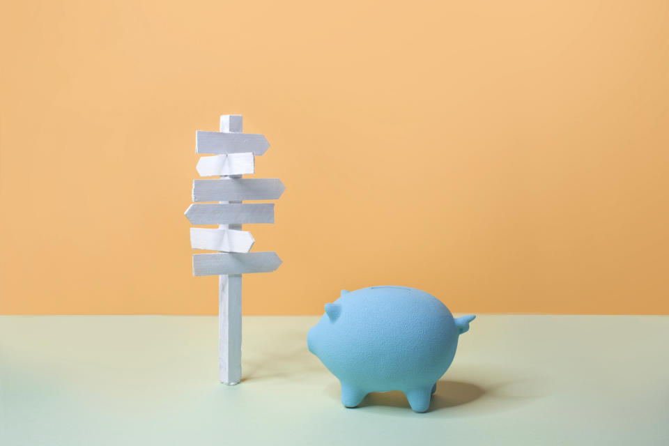 One big piggy bank and an empty road sign on coloured background.