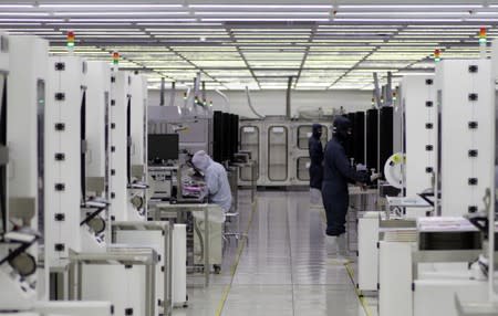 FILE PHOTO: Workers monitor microchip production in the clean room at the UTAC plant in Singapore