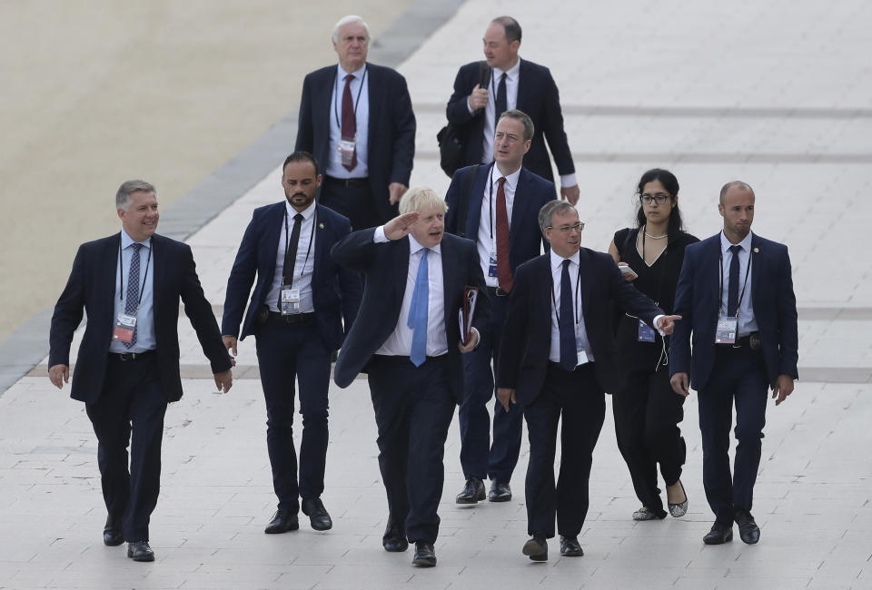 FILE - In this Monday, Aug. 26, 2019 file photo Britain's Prime Minister Boris Johnson, center, salutes people as he walks along the seafront in Biarritz, France ahead of the third and final day of the G-7 summit, . (AP Photo/Markus Schreiber)