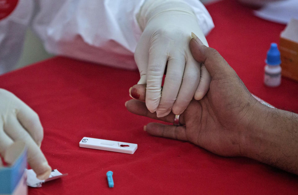 A military paramedic collects a blood sample for a coronavirus antibody test at a testing site in Medan, North Sumatra, Indonesia, Wednesday, May 27, 2020. (AP Photo/Binsar Bakkara)