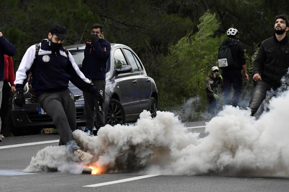 A protester kicks a tear gas canister thrown by riot police during clashes in Karava near the area where the government plans to build a new migrant detention center, on the northeastern Aegean island of Lesbos, Greece, Wednesday, Feb. 26, 2020. Local authorities declared a 24-hour strike on two eastern Greek islands Wednesday to protest government plans to build new migrant detention camps there. (AP Photo/Michael Varaklas)