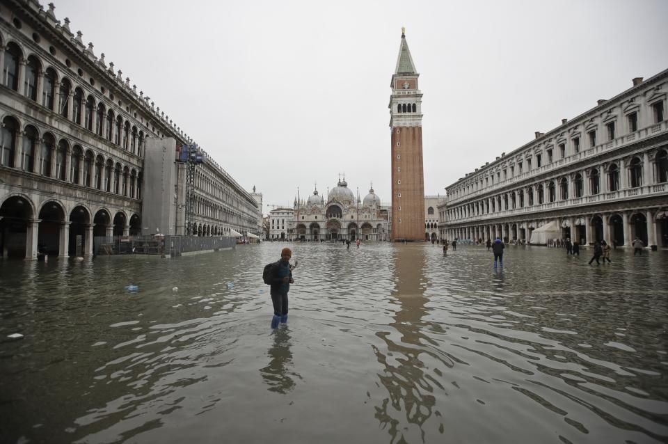 People wade through water in a flooded St. Mark's Square, in Venice, Wednesday, Nov. 13, 2019. The high-water mark hit 187 centimeters (74 inches) late Tuesday, Nov. 12, 2019, meaning more than 85% of the city was flooded. The highest level ever recorded was 194 centimeters (76 inches) during infamous flooding in 1966. (AP Photo/Luca Bruno)