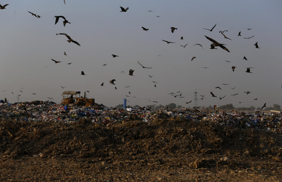 In this Tuesday, Dec. 4, 2018 photo crows and black kites fly next to a tractor working on a garbage-dump on the outskirts of Islamabad, Pakistan. As politicians haggle at a U.N. climate conference in Poland over ways to limit global warming, the industries and machines powering our modern world keep spewing their pollution into the air and water. The fossil fuels extracted from beneath the earth’s crust _ coal, oil and gas _ are transformed into the carbon dioxide that is now heating the earth faster than scientists had expected even a few years ago. (AP Photo/Anjum Naveed)