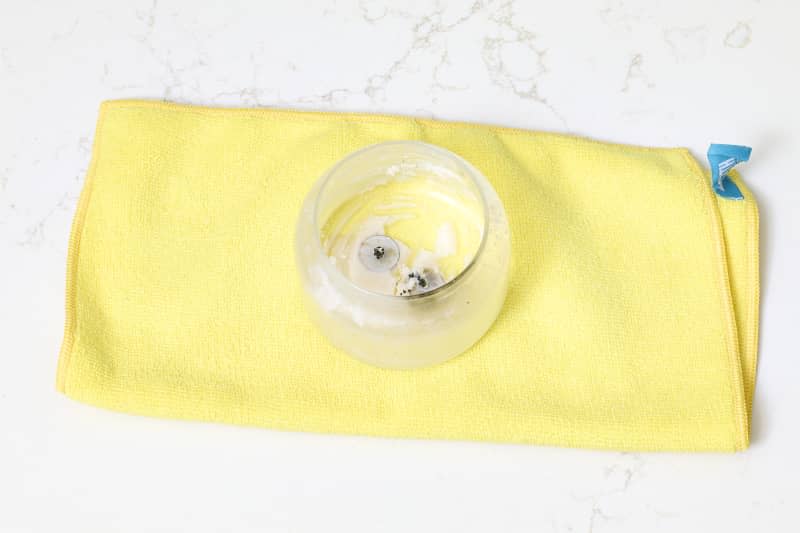 overhead shot of an emptied candle jar on a yellow microfiber towel.