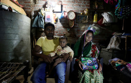 Bahadur Nishad holds his son Divaker, 2, as his wife Nandini (R) displays a picture of their son Deepak, 4, who died in the Intensive care unit in the Baba Raghav Das hospital in Gorakhpur district, India August 13, 2017. REUTERS/Cathal McNaughton