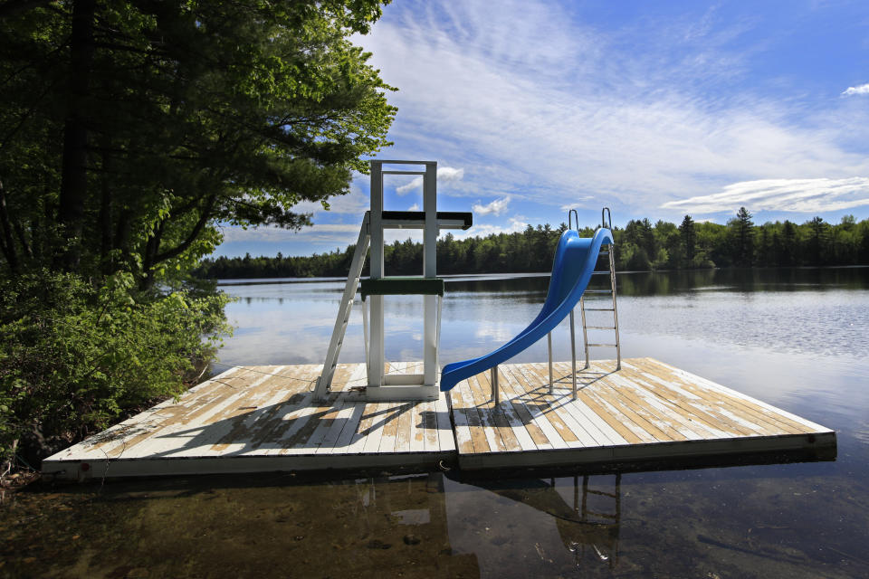 In this Thursday, June 4, 2020 photo, a slide on a floating dock is parked near the shore of Echo Lake at the the Camp Winnebago summer camp, in Fayette, Maine. The boys camp is going ahead with plans to open with a reduction in the number of campers and other changes to comply with guidelines for helping prevent the spread of the coronavirus. Many of the nation's 15,000-plus summer camps opting to close because of health concerns surrounding the pandemic, or because of delays in receiving rules or guidelines from licensing officials. (AP Photo/Robert F. Bukaty)