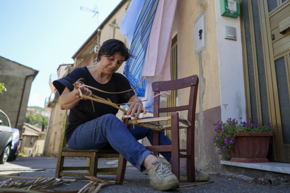 Lina Fazio straws a traditional chair in front of hot house, in Serrastretta, southern Italy, Friday, July 8, 2022. From a rustic, tiny synagogue she fashioned from her family's ancestral home in this mountain village, American rabbi Aiello is keeping a promise made to her Italian-born father: to reconnect people in this southern region of Calabria to their Jewish roots, links nearly severed five centuries ago when the Inquisition forced Jews to convert to Christianity. (AP Photo/Andrew Medichini)