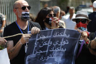 Lebanese anti-government activists protest outside a Lebanese court, as they demand the improving judicial independence, in Beirut, Lebanon, Wednesday, June 17, 2020. A year after anti-government protests roiled Lebanon, dozens of protesters are being tried before military courts that human rights lawyers say grossly violate due process and fail to investigate allegations of torture and abuse. The Arabic placard reads:"You can imprison a revolutionary but you cannot imprison the revolution." (AP Photo/Hussein Malla)