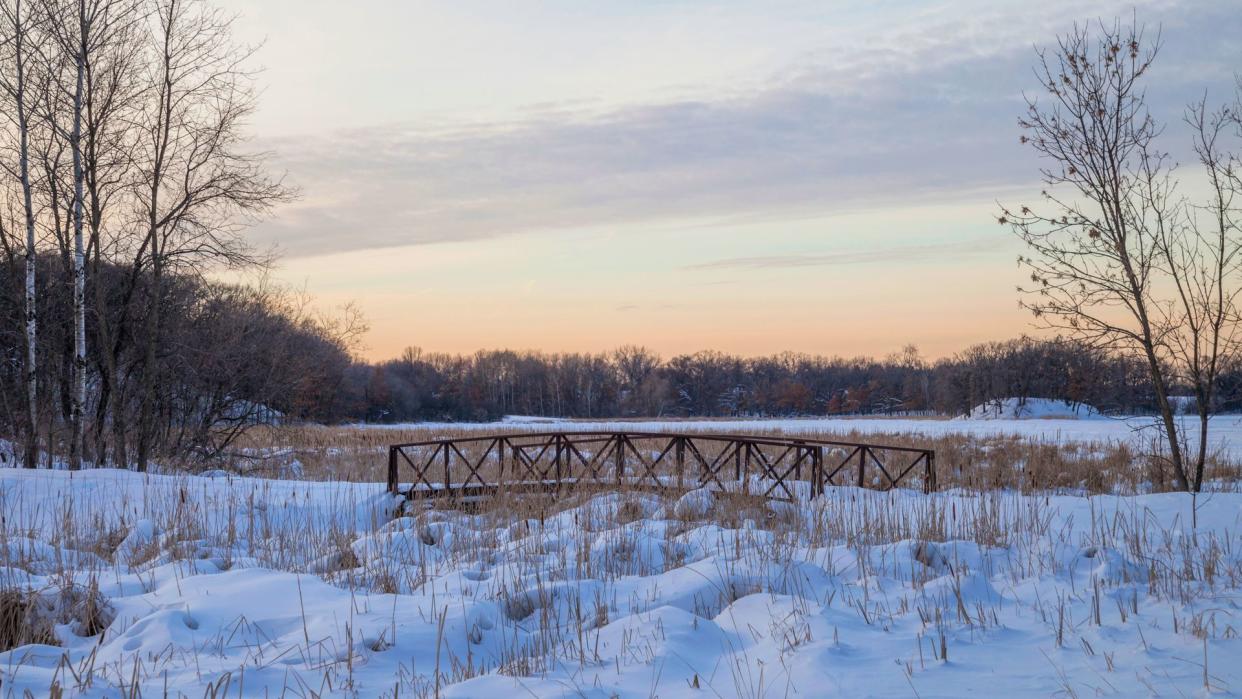 A Medium Shot of a Walking Bridge in a Snowy Suburban Minnesota Landscape during a Winter Golden Hour - Image.