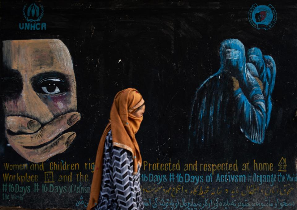 A woman walks past a mural calling for women and children's rights in Bamian, Afghanistan.