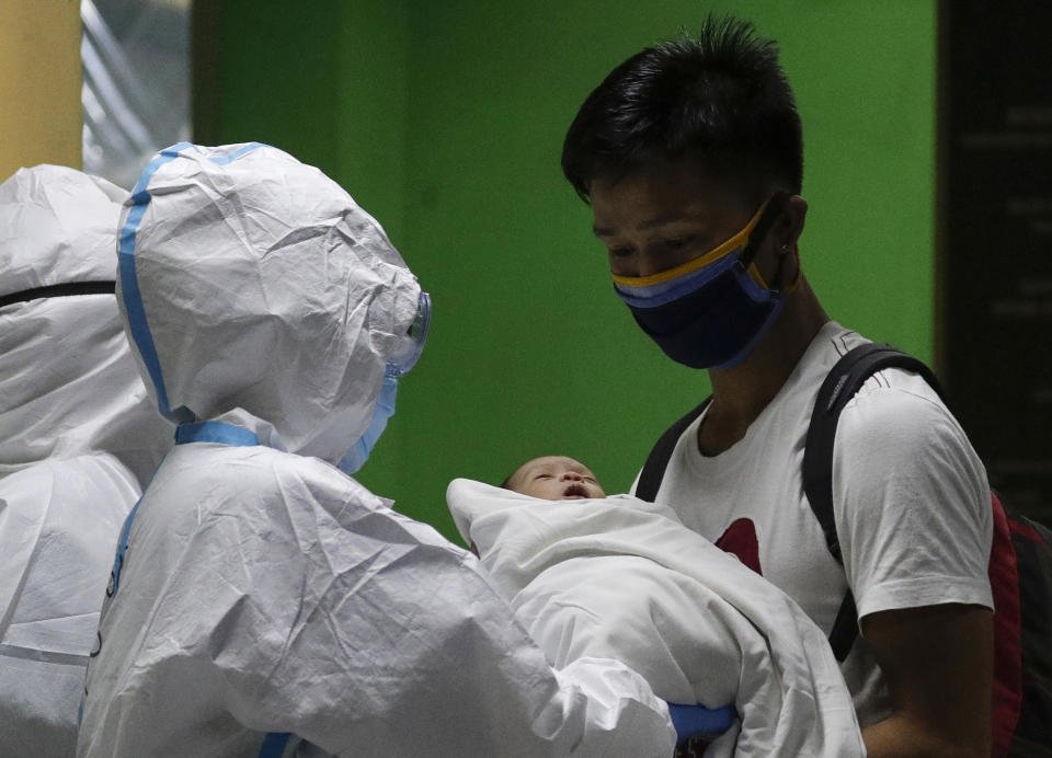 FILE - In this April 28, 2020, file photo, Ronnel Manjares, right, receives his 16-day-old baby Kobe who recovered from COVID-19 as they discharge him from the National Children's Hospital in Quezon city, Metro Manila, Philippines. Kobe was heralded as the country's youngest COVID-19 survivor. But the relief and joy proved didn't last. Three days later, Kobe died on June 4 from complications of Hirschsprung disease, a rare birth defect. (AP Photo/Aaron Favila, File)