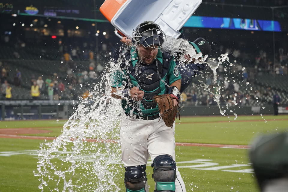Seattle Mariners catcher Cal Raleigh has water and ice dumped onto him by teammate Tom Murphy as Raleigh takes part in an interview after the Mariners defeated the Oakland Athletics 4-3 in a baseball game Friday, July 23, 2021, in Seattle. (AP Photo/Ted S. Warren)