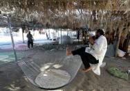 Workers take a break from making fishing cages in Kalba in the UAE, with one leaping over the metre-high cage using a rope from the roof