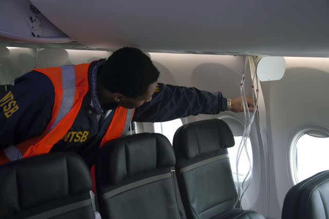 <p>NTSB via Getty</p> A member of the NTSB examines the fuselage of Alaska Airlines Flight 1282