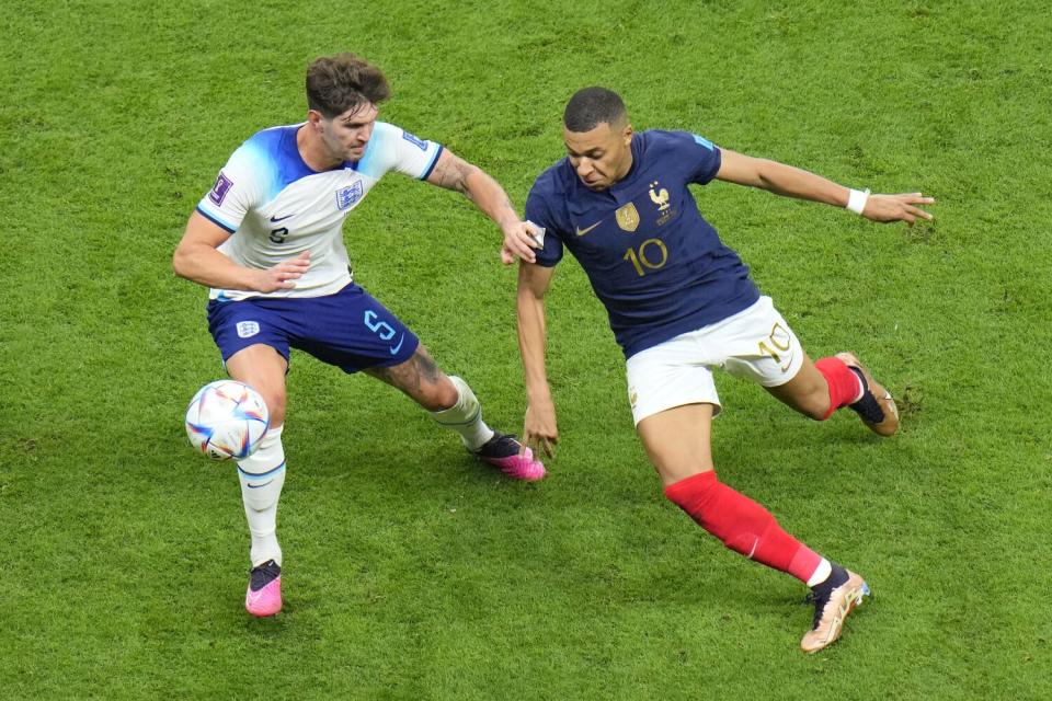 England's John Stones, left, challenges France's Kylian Mbappe for the ball.