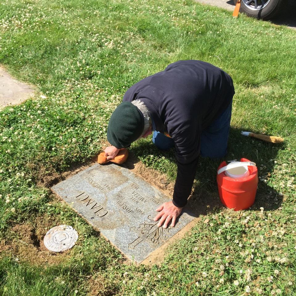 Tom Duffey washes the grave marker of fellow Green Beret Orlando Cianci at St. Ann’s cemetery last week.