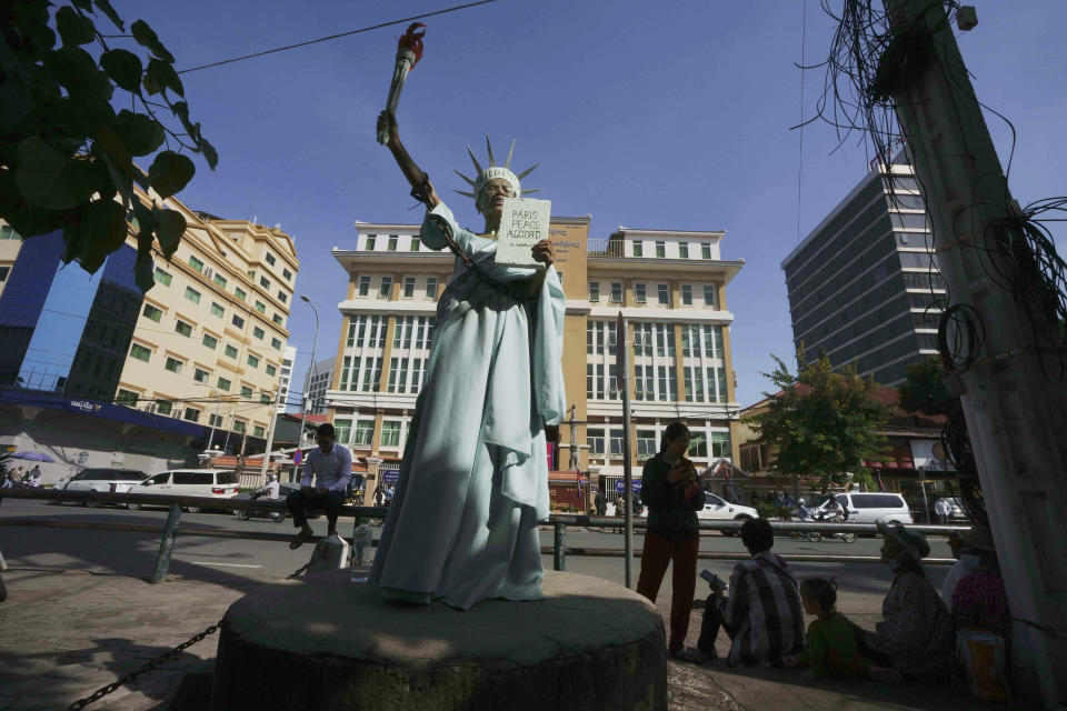 Cambodian-American lawyer Theary Seng, dressed in the Lady Liberty, stands outside the Phnom Penh Municipal Court in Phnom Penh, Cambodia, Tuesday, June 14, 2022. The Cambodian American lawyer and dozens of members of a now-dissolved opposition party were convicted of treason Tuesday in a trial that was the latest move to tame all opposition to the long-running rule of Prime Minister Hun Sen. (AP Photo/Heng Sinith)