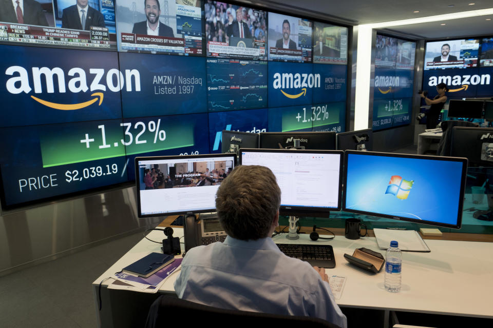 FILE- In this Sept. 4, 2018, file photo a Nasdaq employee monitors market activity in New York, with Amazon's logo on display in the background. Germany’s finance minister on Wednesday welcomed an agreement requiring large companies in the European Union to reveal how much tax they paid in which country. The deal was struck late Tuesday between representatives of the EU’s 27 member states and the European Parliament. (AP Photo/Mark Lennihan, File)